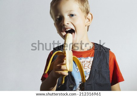 close-up portrait of Funny Child eating Banana.Happy Little Boy. Health food. Fruits.Vitamin
