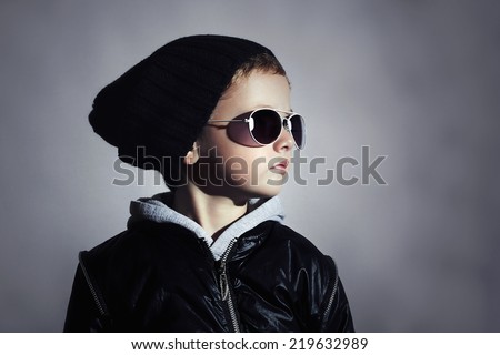 Fashionable child boy in sunglasses. Kid in Black cap. Autumn style. Winter. Underground background.Little boy.Serious Preschooler.Children fashion