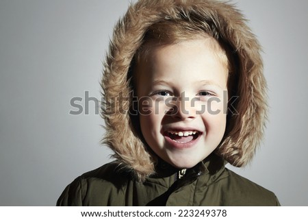 Smiling child in fur hood and winter jacket. fashion kid.children.close-up.parka.little boy winter style