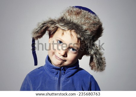 funny child in fur Hat.fashion casual winter style.little boy in blue sport sweater.children emotion