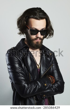 Portrait of a young bearded man in a leather jacket. Hipster in sunglasses