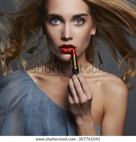 beautiful girl with red lipstick. young Woman putting lipstick. healthy hair