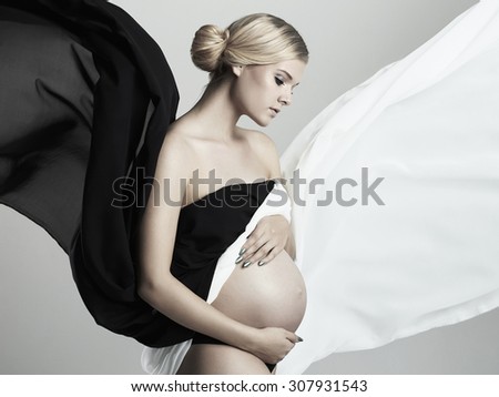 young beautiful pregnant woman.flying fabric.fashion portrait of Blond girl with belly