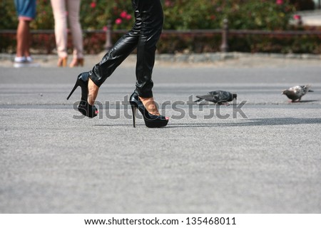 woman walking in high heels on the road next to pigeons