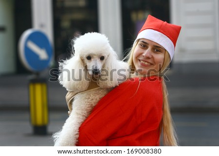 BELGRADE, SERBIA - December 29, 2013: Blonde girl with a dog, People in Santa Claus costumes take part in the annual race in downtown Belgrade, December 29, 2013, in Belgrade, Serbia