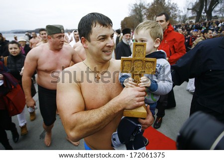 ZEMUN, SERBIA - JAN 19, 2014: The winner lifts up a cross. The Serbian Orthodox Church, SPC, traditionally marks Epiphany with competitions to retrieve the Holy Cross from Danube river in Zemun.