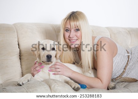 Woman sitting on the white sofa with white labrador puppy