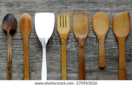 vintage kitchen spatulas and spoons on  board with one standing out from the crowd