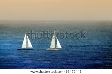 Two sailboats in blue ocean and twilight