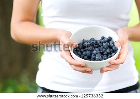 Young woman holding bowl filled blueberries