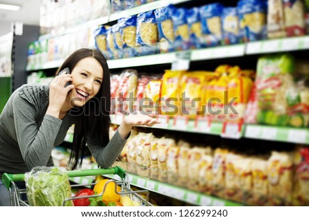 Beautiful woman on mobile phone at supermarket