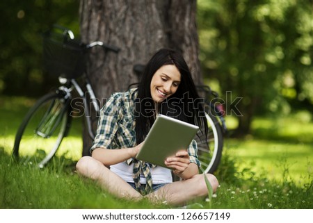 Beautiful young woman using digital tablet outdoors