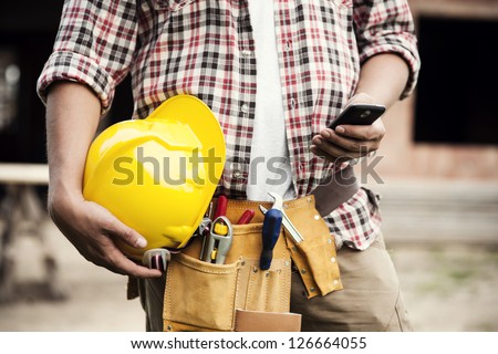 Close-up of construction worker sending text on mobile phone