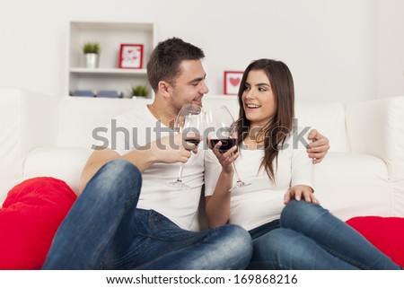 Happy couple spending romantic time with red wine at home