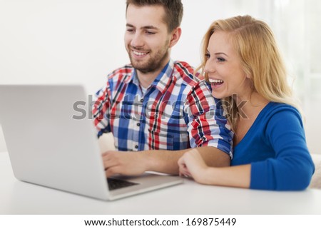 Laughing couple using computer at home