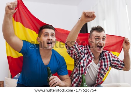 Men watching football match on TV and cheering of spanish team