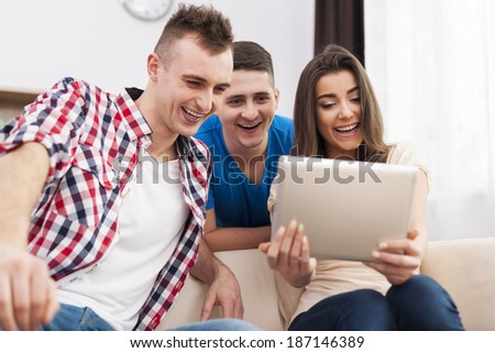 Laughing friends with digital tablet at home