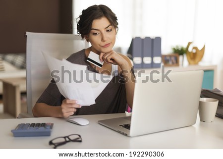 Pensive woman paying bills at home