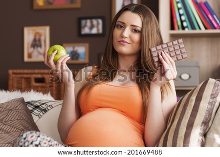 Pregnant woman considering the choice of healthy and unhealthy food