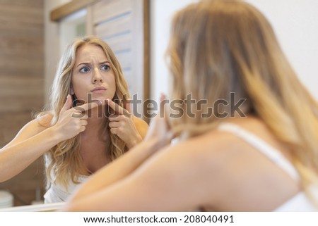 Angry woman squeezing  pimple from face