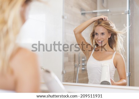 Natural woman in front of mirror drying hair