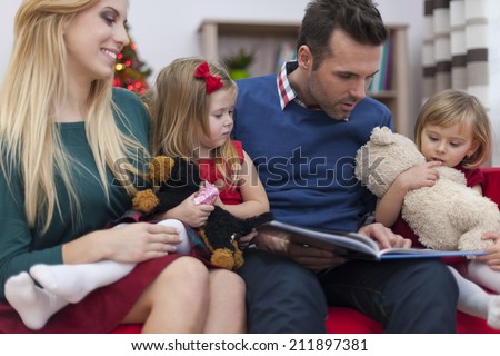 Dad reading book for his little daughters in christmas time