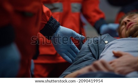 Closeup male patient lying on stretchers in ambulance car. Tired man having pain in stomach. Unrecognizable paramedics in medical gloves providing firs aid help to victim on stretchers. Rescue concept ストックフォト © 