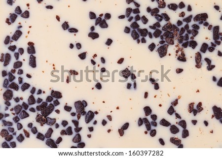 White chocolate with dark grains background, close up