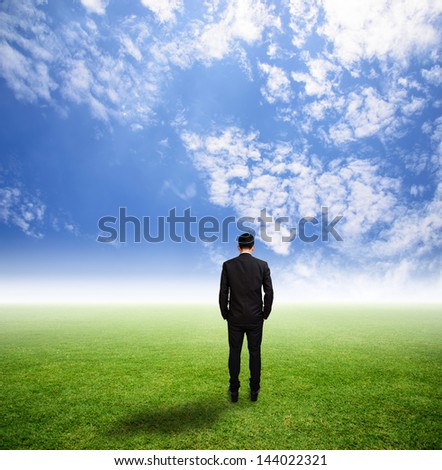 Businessman stand alone on grass field has hazy