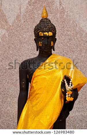 image of black Buddha covers a body with silk yellow gold cloth with marble wall and church shade