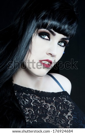 beautiful brunette with dark gothic makeup, white skin and red lips looking like a vampire
