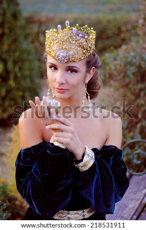 Elegant young woman dressed like queen with a crown holding an apple