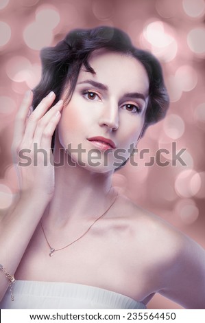 Beautiful brunette woman with evening makeup on peach bokeh background