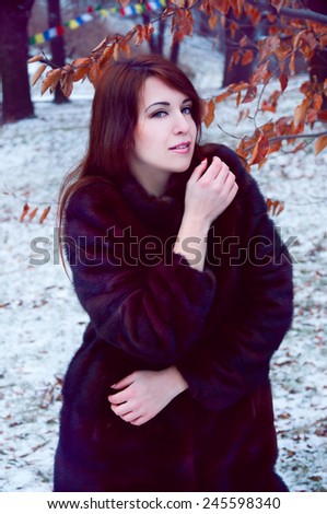 Outdoor winter portrait of beautiful smiling redheaded woman in fur coat