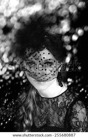 Elegant young woman in black lace dress and black veil hat with long curly hair. Retro style.