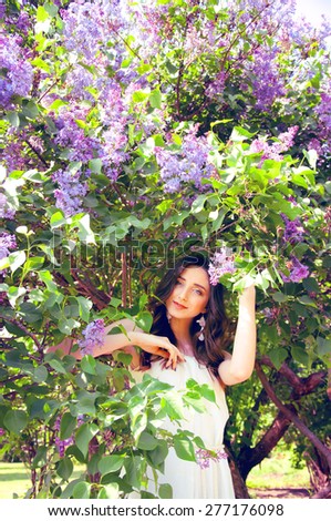 Woman with long brown hair in lilac bushes on a sunny day