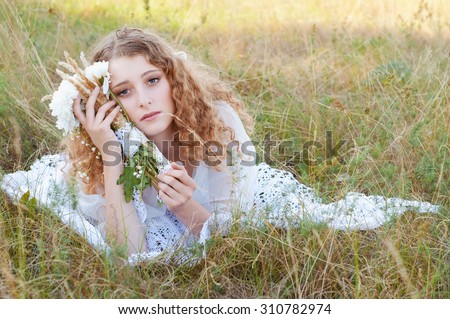 Woman in white dress with curly golden hair resting her head on her hand