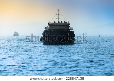 Front of a small cargo vessel at the evening sea with further ships at the background horizon/Freight Ship at Wide Sea