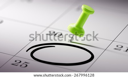 Concept image of a Calendar with a shiny green push pin. Closeup shot of a thumbtack attached.