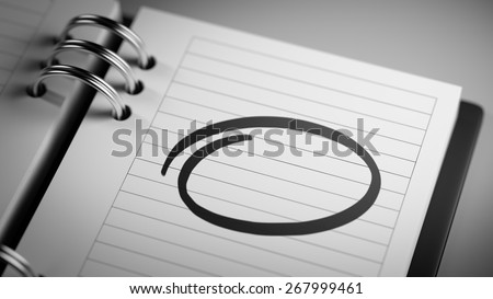 Closeup of a personal agenda, organizer or planner, setting an important date, marking a day of the month representing a organizing time and schedule.