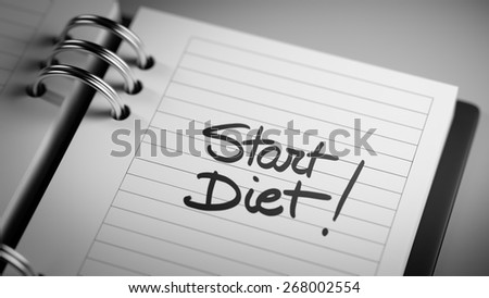 Closeup of a personal agenda marking a day of the month representing a organizing time and schedule. Start Diet text note reminder concept. Words Start Diet written in Black Marker.