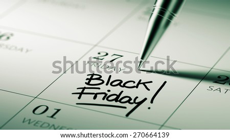 Closeup of a personal agenda setting an important date written with pen. The words Black Friday written on a white notebook to remind you an important appointment.
