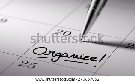 Closeup of a personal agenda setting an important date written with pen. The words Organize written on a white notebook to remind you an important appointment.