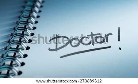 Closeup of a personal calendar setting an important date representing a time schedule. The words Doctor written on a white notebook to remind you an important appointment.