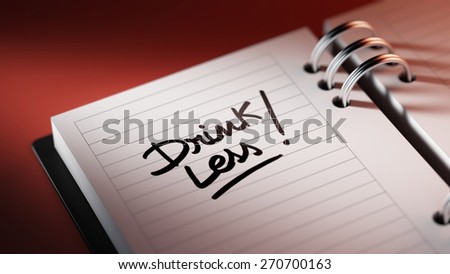 Closeup of a personal agenda setting an important date representing a time schedule. The words Drink Less written on a white notebook to remind you an important appointment.