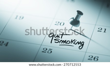 Concept image of a Calendar with a push pin. Closeup shot of a thumbtack attached. The words Quit Smoking written on a white notebook to remind you an important appointment.