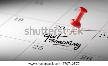 Concept image of a Calendar with a red push pin. Closeup shot of a thumbtack attached. The words Quit Smoking written on a white notebook to remind you an important appointment.