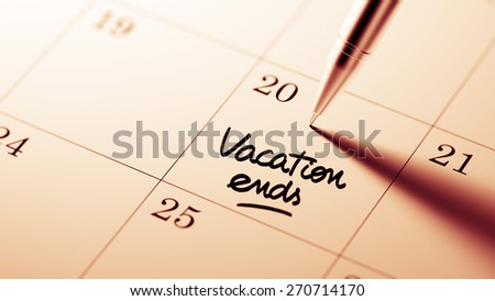 Closeup of a personal agenda setting an important date written with pen. The words Vacation ends written on a white notebook to remind you an important appointment.
