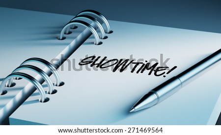Closeup of a personal agenda setting an important date writing with pen. The words Showtime written on a white notebook to remind you an important appointment.