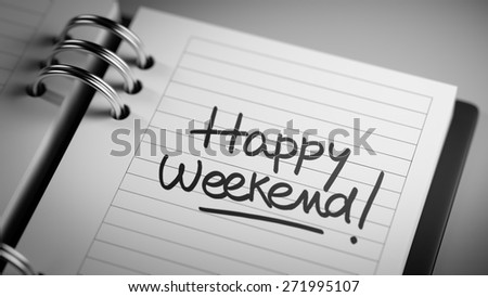 Closeup of a personal agenda setting an important date representing a time schedule. The words Happy Weekend written on a white notebook to remind you an important appointment.
